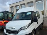 une camionnette blanche garée devant un immeuble, avec un bulldozer en arrière-plan