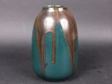 a blue and brown vase sitting on a gray surface