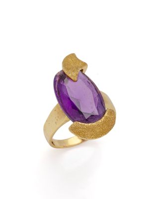 un gros plan d'une bague en pierre violette sur fond blanc