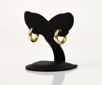 une paire de boucles d'oreilles créoles en or posées sur un support noir, sur fond blanc