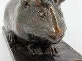 bronze sculpture of a guinea on a wooden base on a white background
