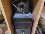 a computer in the corner of a cabinet with a lot of wires on it
