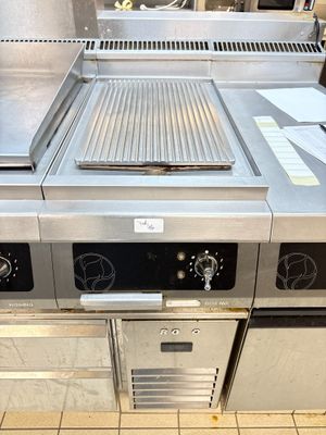 une grande cuisine professionnelle équipée d'une cuisinière et d'un grill