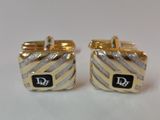 two pairs of gold and silver cufflinks with a black and white logo