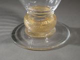 a clear glass cup with a gold base on a plate