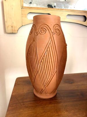 un vase marron posé sur une table en bois, avec un miroir en arrière-plan
