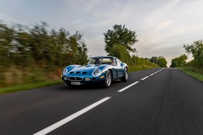 the blue sports car is driving down the road on the side of the road