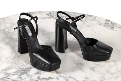 Ce sont des chaussures noires à talons hauts posées sur une table en marbre