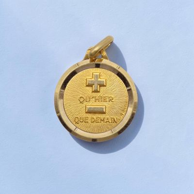 une pièce d'or sur laquelle est gravée une croix, sur un fond bleu
