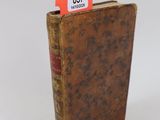 un vieux livre portant une étiquette rouge, posé sur une surface blanche