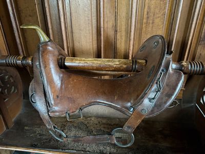a brown horse saddle sitting on top of a wooden shelf