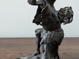 a statue of a man sitting on top of a wooden table