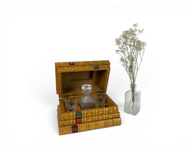 a glass vase with flowers in it next to a box of books