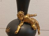 a black vase with a gold figurine on top of it