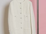 une veste blanche suspendue à un portant devant un mur rayé de rose et de blanc