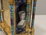a gold clock with a picture of a woman on it