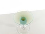 a small glass vase with a green candle inside of it
