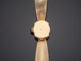 a gold wrist watch with a mesh band