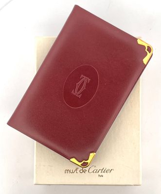 MUST de CARTIER. Répertoire à couverture en cuir bordeaux monogrammé e