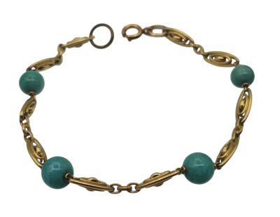 un gros plan d'un bracelet orné de perles vertes sur fond blanc