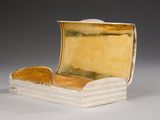 a silver and gold box with a book on top of it