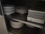 many plates stacked on a shelf in the kitchen
