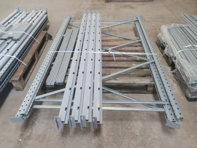 Plusieurs pièces métalliques sont empilées sur des palettes dans un entrepôt