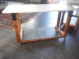 une table blanche avec un piètement en bois posée sur un sol carrelé