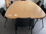 une grande table en bois avec des chaises noires dans une pièce
