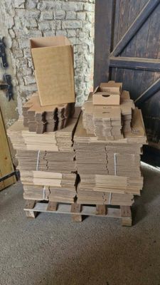 une pile de cartons posée sur une palette devant un mur de briques