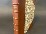 a brown book with a gold cover sitting on top of a table