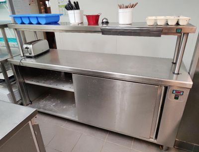 un plan de travail en acier inoxydable dans une cuisine professionnelle, sur lequel sont posés des casseroles et des ustensiles