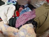 a basket full of clothes that is sitting on a bed
