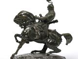 bronze statue of a man on a horse on a wooden base