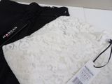 a white lace top and black pants on a white table