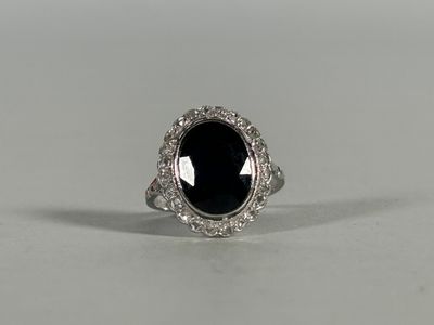 a black stone and diamond ring on a white surface