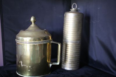 une cafetière en or à côté d'une cafetière en argent, posées sur un tissu noir