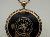 une montre de poche noire et dorée ornée d'un lion