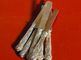 five silverware knives on a red surface