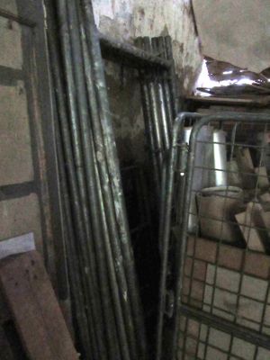 un tas de tuyaux métalliques dans une pièce, à côté d'un tas de bois