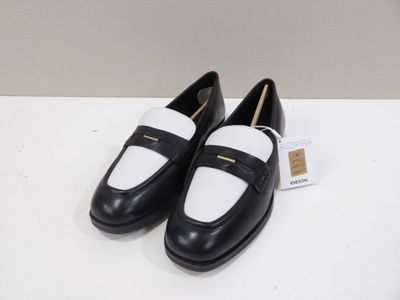 a pair of black and white shoes on a white table