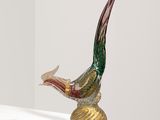 une sculpture en verre représentant un oiseau perché sur un socle