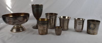 many silver cups and cups sitting on a white table