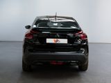 the rear end of a black car parked in a white room