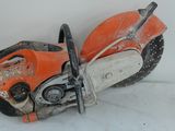 une tronçonneuse orange et noire posée sur une surface blanche