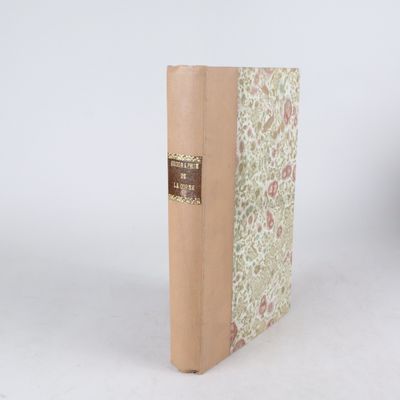 un vieux livre à la couverture marron posé sur une table blanche
