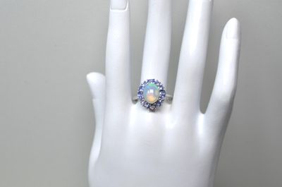 une main blanche portant une bague sertie d'un oplite
