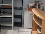 une pièce équipée d'un bureau, d'étagères et d'un réfrigérateur