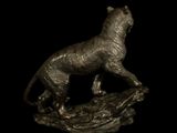 bronze statue of a cheetah on a rock on a black background