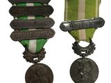 deux médailles sont représentées sur un fond blanc, ornées d'un ruban vert